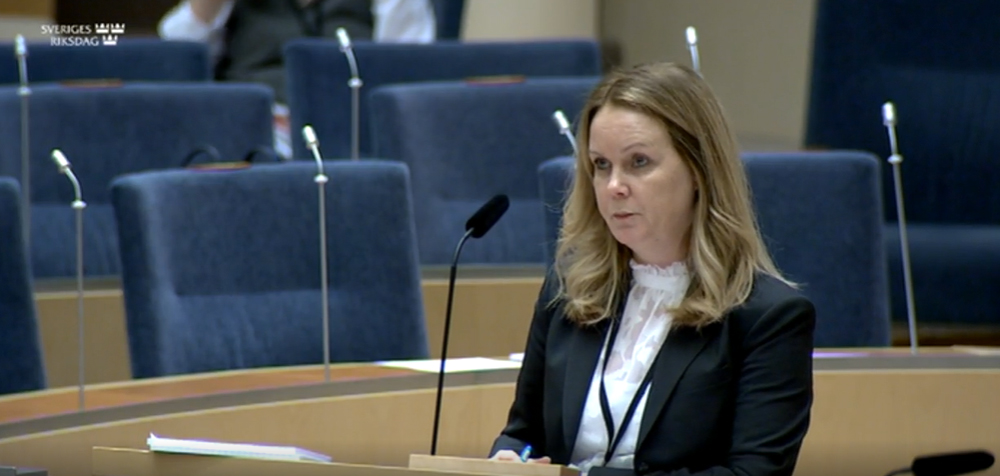 Jennie Nilsson står vid talarstolen i riksdagen.