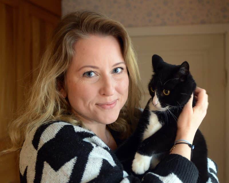 Svartvit katt bärs av en ung kvinna med svartvit tröja